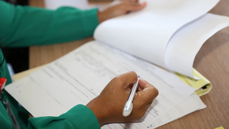 Persona rellenando documentación administrativa relacionada con subvenciones para entidades locales y gestión de colonias felinas.